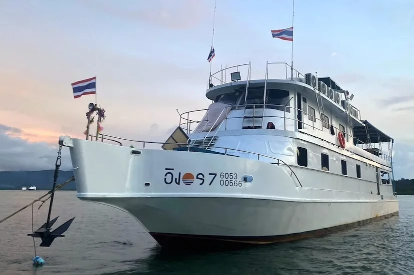 Grand bateau de plongée blanc amarré en mer sous un ciel coloré