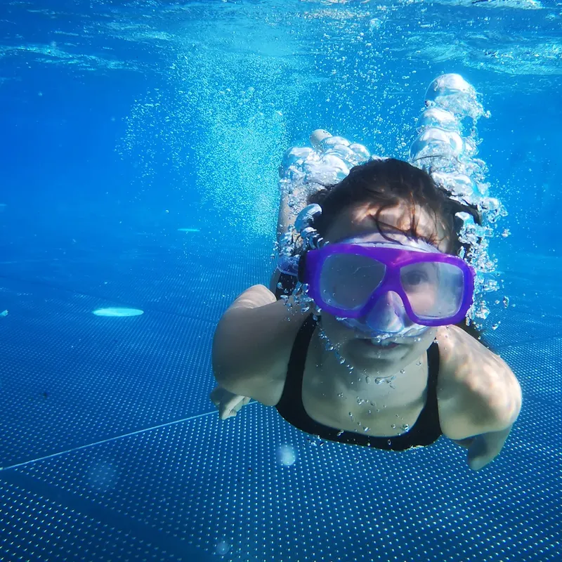 Jeune femme nageant avec masque et tuba dans une piscine bleue