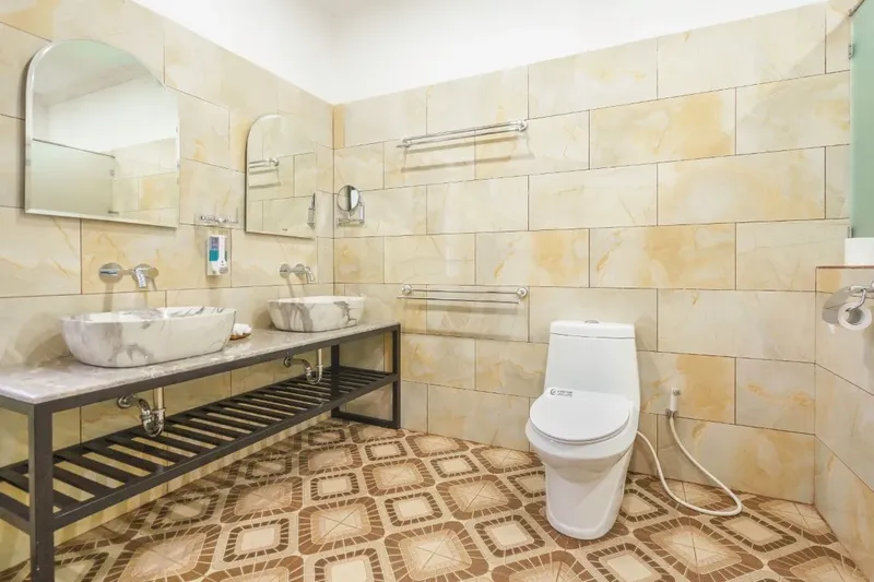 Salles de bain avec lavabos en marbre, toilettes et carrelage décoratif