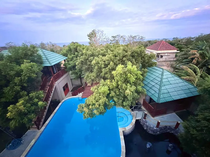 Vue aérienne d'un complexe hôtelier avec piscine et végétation luxuriante