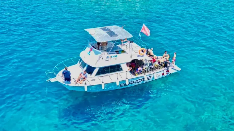 Bateau de plongée rempli de personnes sur une mer turquoise ensoleillée