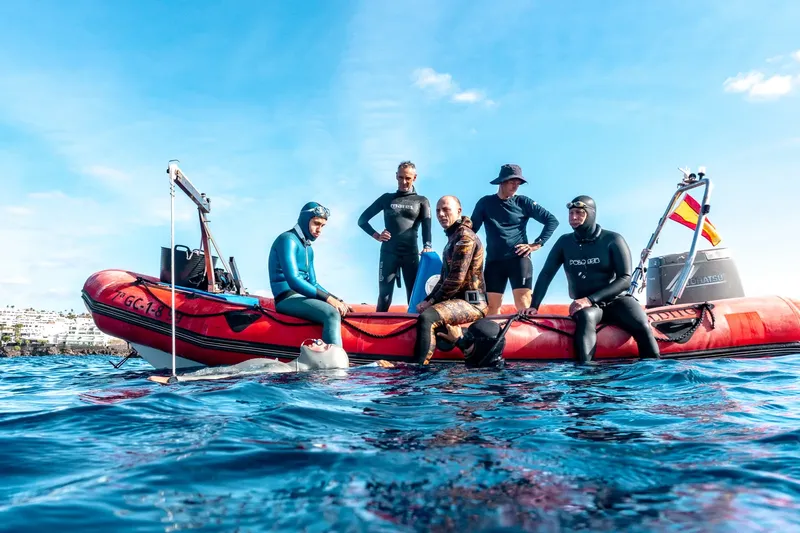 Groupe de plongeurs en combinaison sur un bateau pneumatique rouge