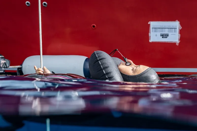 Plongeur en surface, détendeur en bouche, flottant près d'un bateau