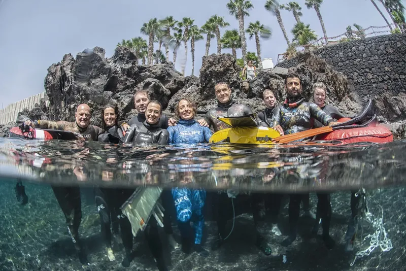 Groupe de plongeurs souriants, moitié hors de l'eau, moitié immergés