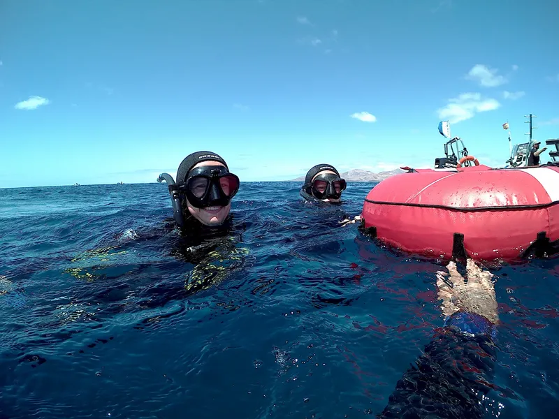 Deux plongeurs en surface près d'un bateau rouge et bleu