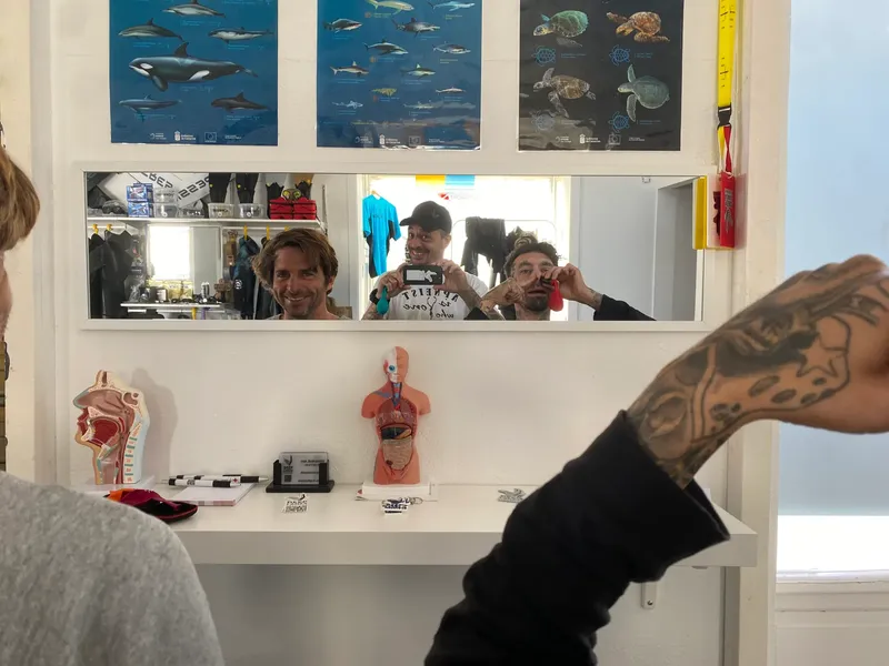 Trois personnes sourient devant un miroir dans une salle blanche