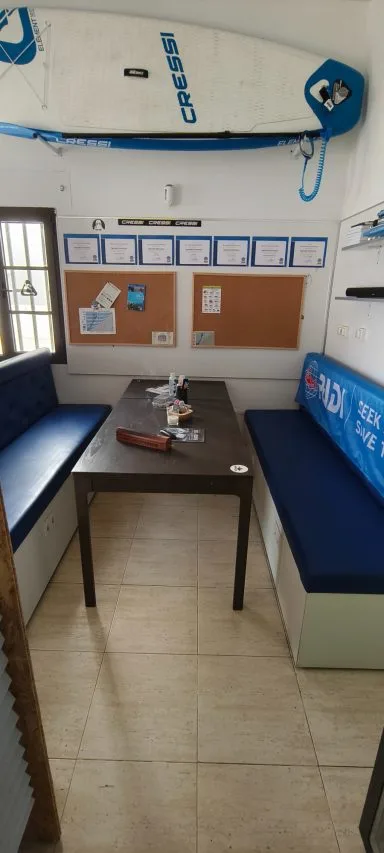 Salle d'attente avec table, banquettes, matériel de plongée et tableau d'affichage