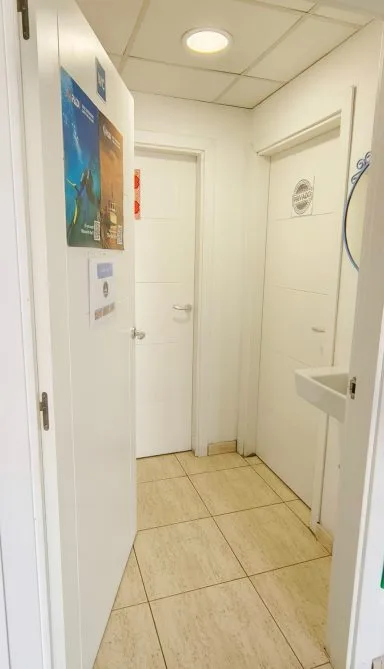 Couloir intérieur blanc avec portes, carrelage clair et affiches murales