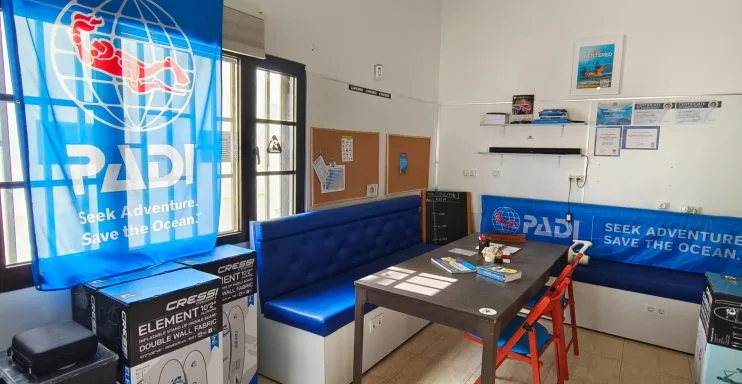 Salle d'attente d'un centre de plongée avec des équipements et des affiches