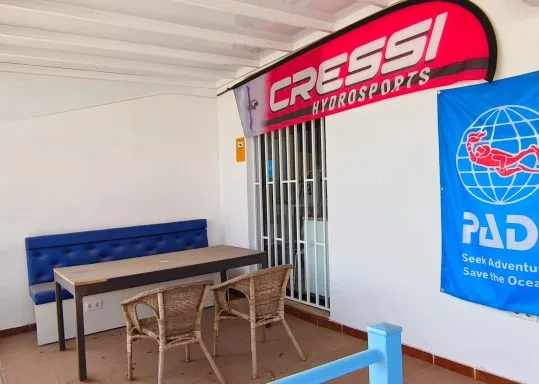 Espace détente avec table, chaises et enseignes de marques de plongée
