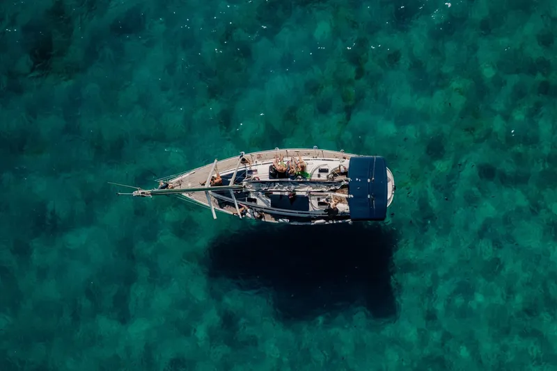 Voilier amarré dans une eau turquoise claire avec des personnes à bord
