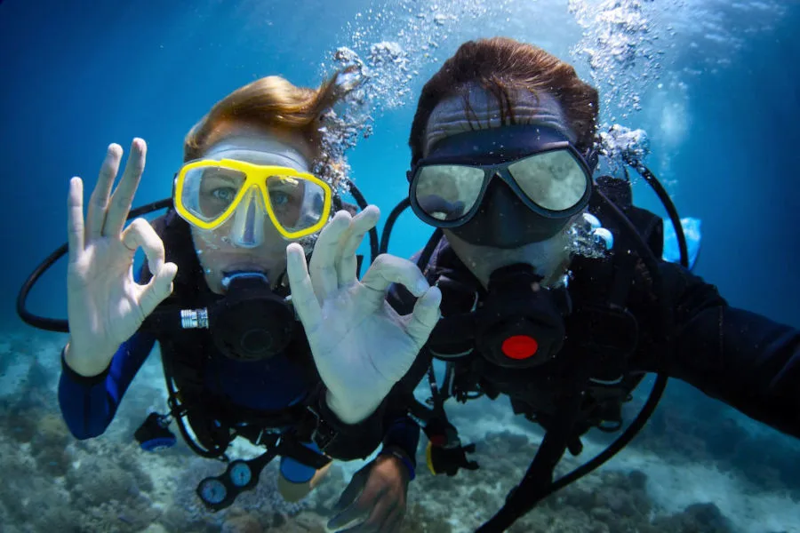 Deux plongeurs souriants font le signe OK sous l'eau