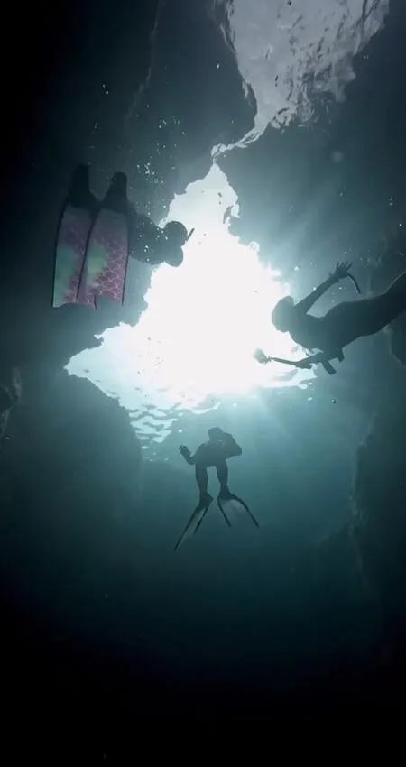 Plongeurs explorent une grotte sous-marine, lumière du soleil filtrant