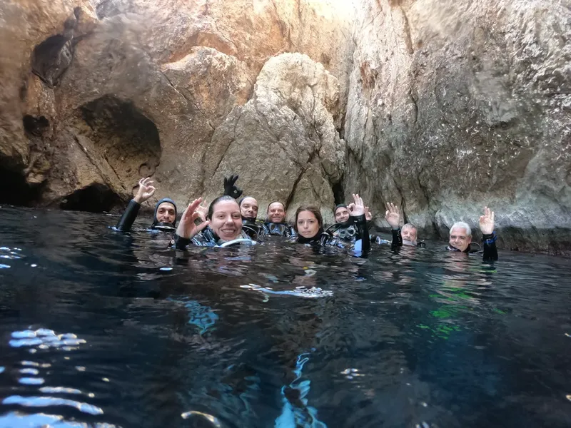 Groupe de plongeurs souriants et faisant signe dans une grotte sous-marine