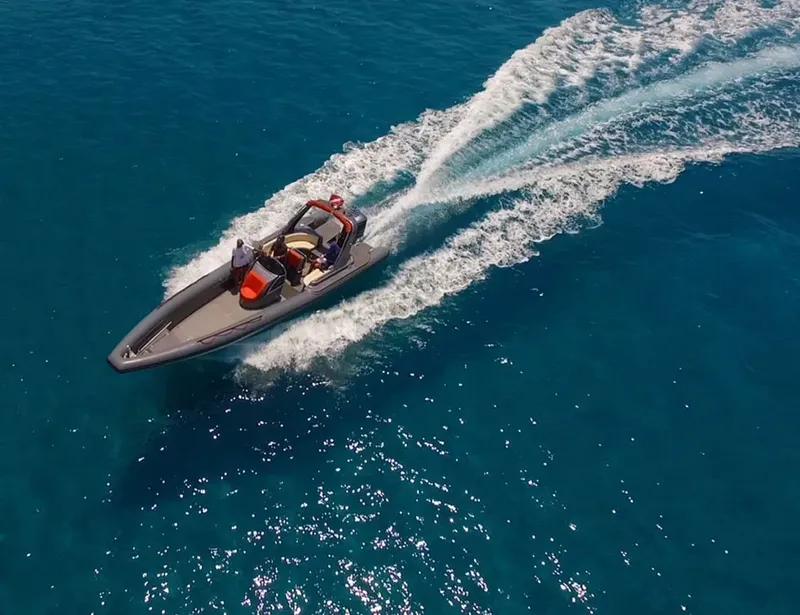 Vue aérienne d'un bateau semi-rigide naviguant sur une mer bleue claire