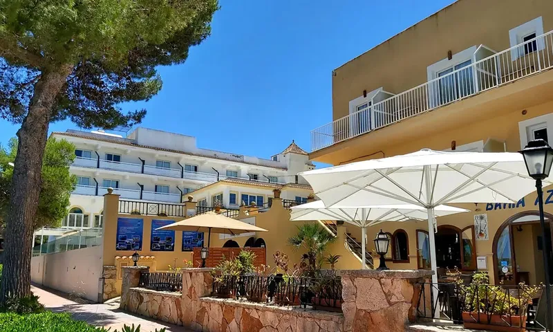 Façade d'un bâtiment avec parasols et végétation sous un ciel bleu