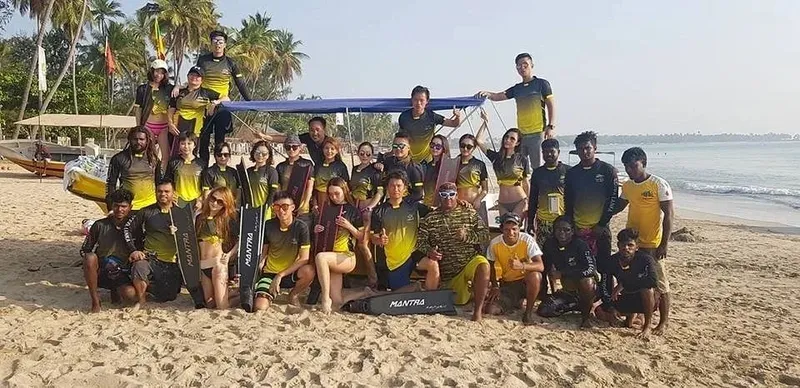 Groupe de personnes souriantes sur une plage tropicale en tenue de plongée