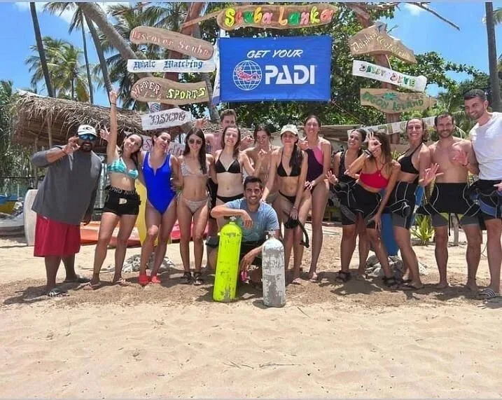 Groupe de personnes souriantes posant avec une bouteille de plongée