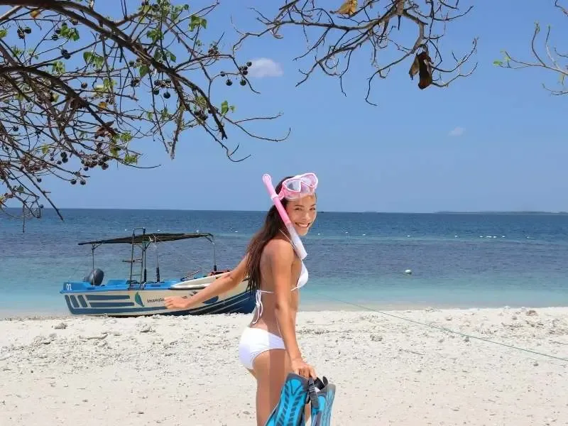 Jeune femme souriante avec masque et palmes sur plage tropicale