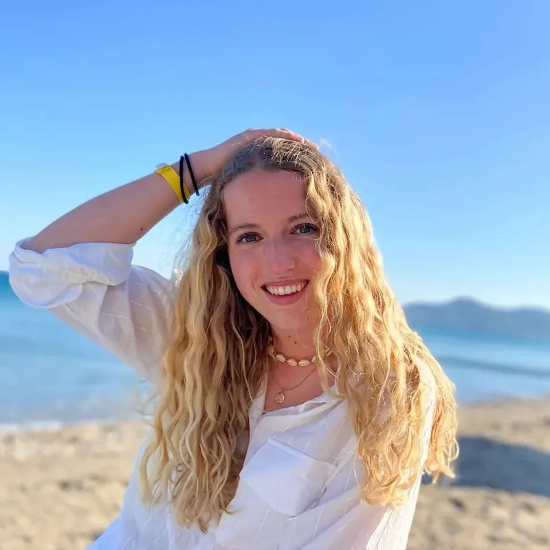 Jeune femme souriante sur une plage ensoleillée avec la mer en arrière-plan