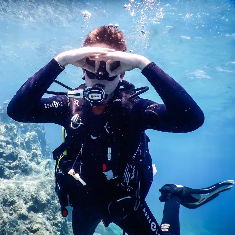 Plongeur avec combinaison noire et masque, regardant vers le haut dans l'eau