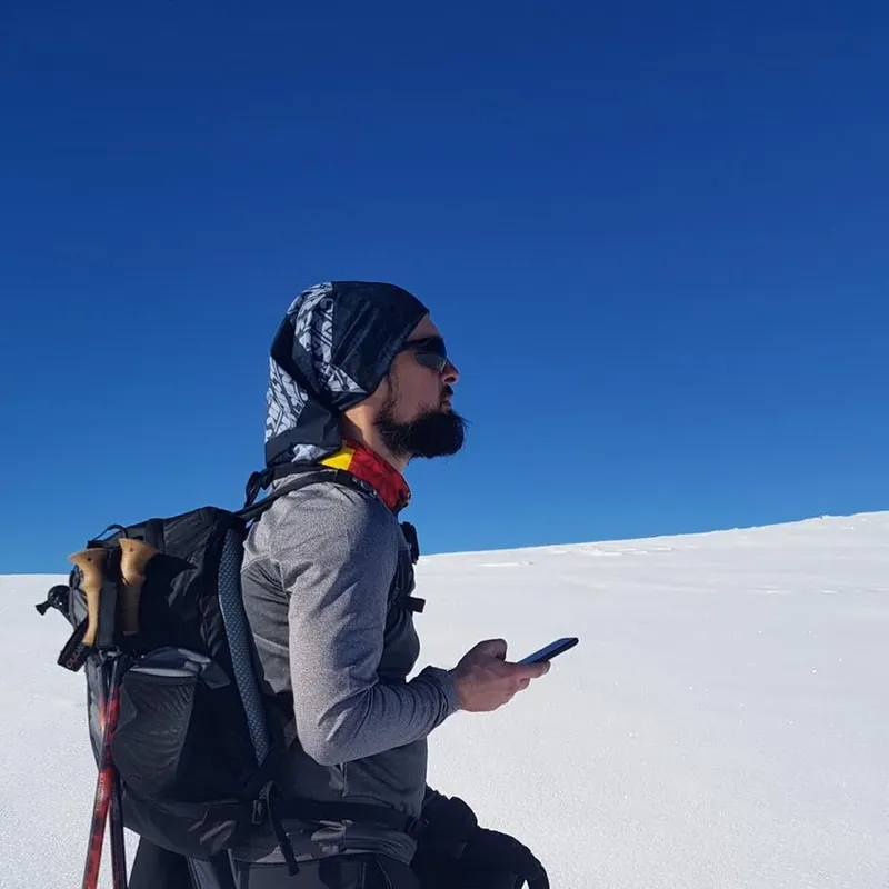 Homme barbu avec un sac à dos utilisant un smartphone en montagne
