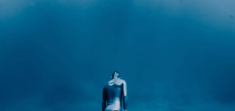 Plongeur seul, dos à la caméra, nageant dans l'eau bleue