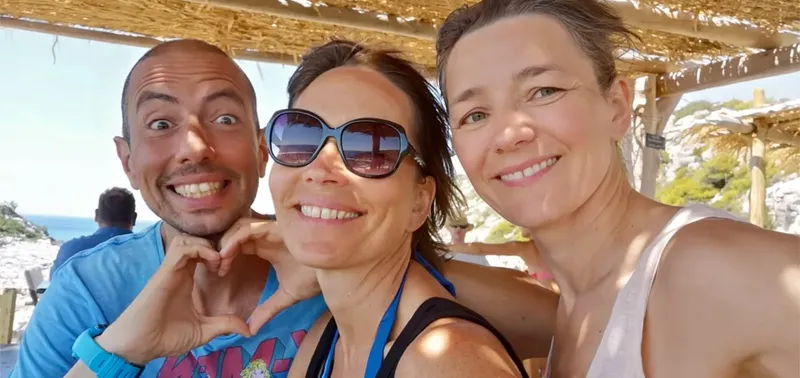 Trois personnes souriantes posent pour un selfie ensoleillé