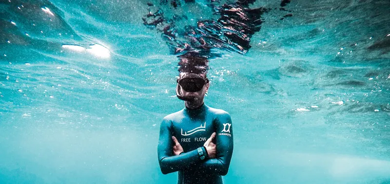 Apnéiste en combinaison, regardant vers le haut dans l'eau turquoise