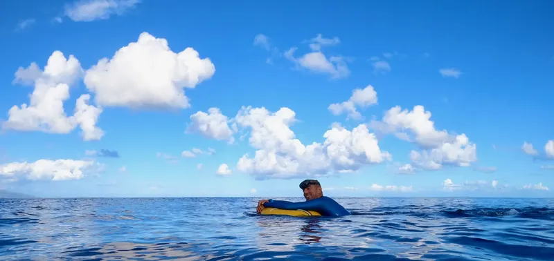 Homme en combinaison flottant à la surface de l'océan bleu