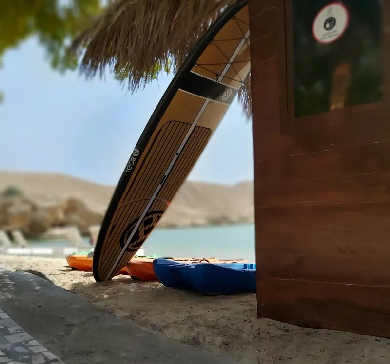 Planche de paddle board adossée à une structure en bois près de l'eau