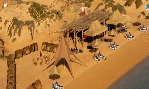 Vue aérienne d'un campement de tentes et de chaises longues sur plage