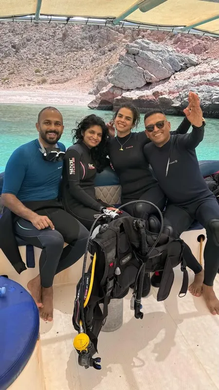 Quatre plongeurs souriants sur un bateau avec du matériel de plongée