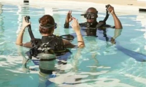 Deux plongeurs en formation, équipés, dans une piscine claire