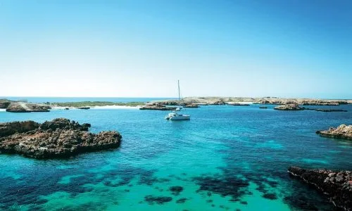 Vue aérienne d'un bateau à voile dans une eau turquoise claire