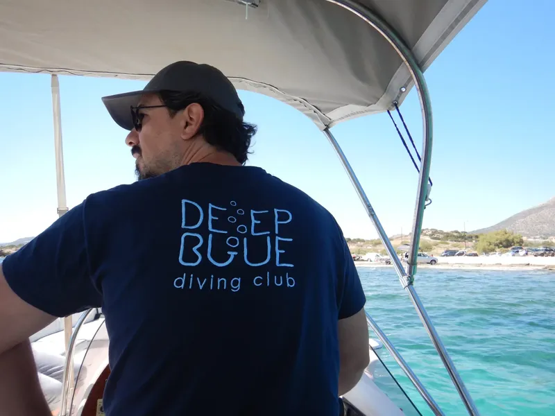 Homme regardant la mer depuis un bateau, portant un t-shirt bleu