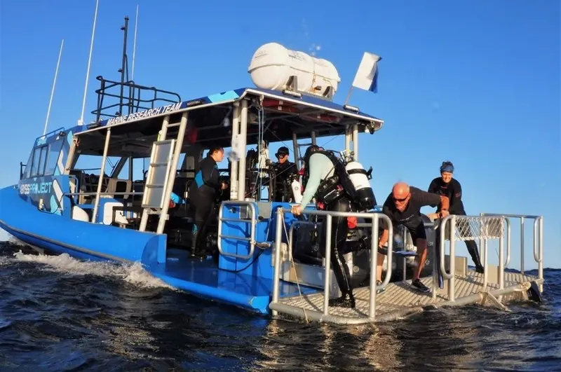 Plongée : des personnes équipées montent à bord d'un bateau bleu en mer