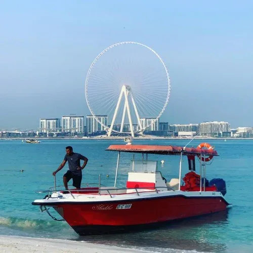 Homme debout sur un bateau rouge amarré sur une plage
