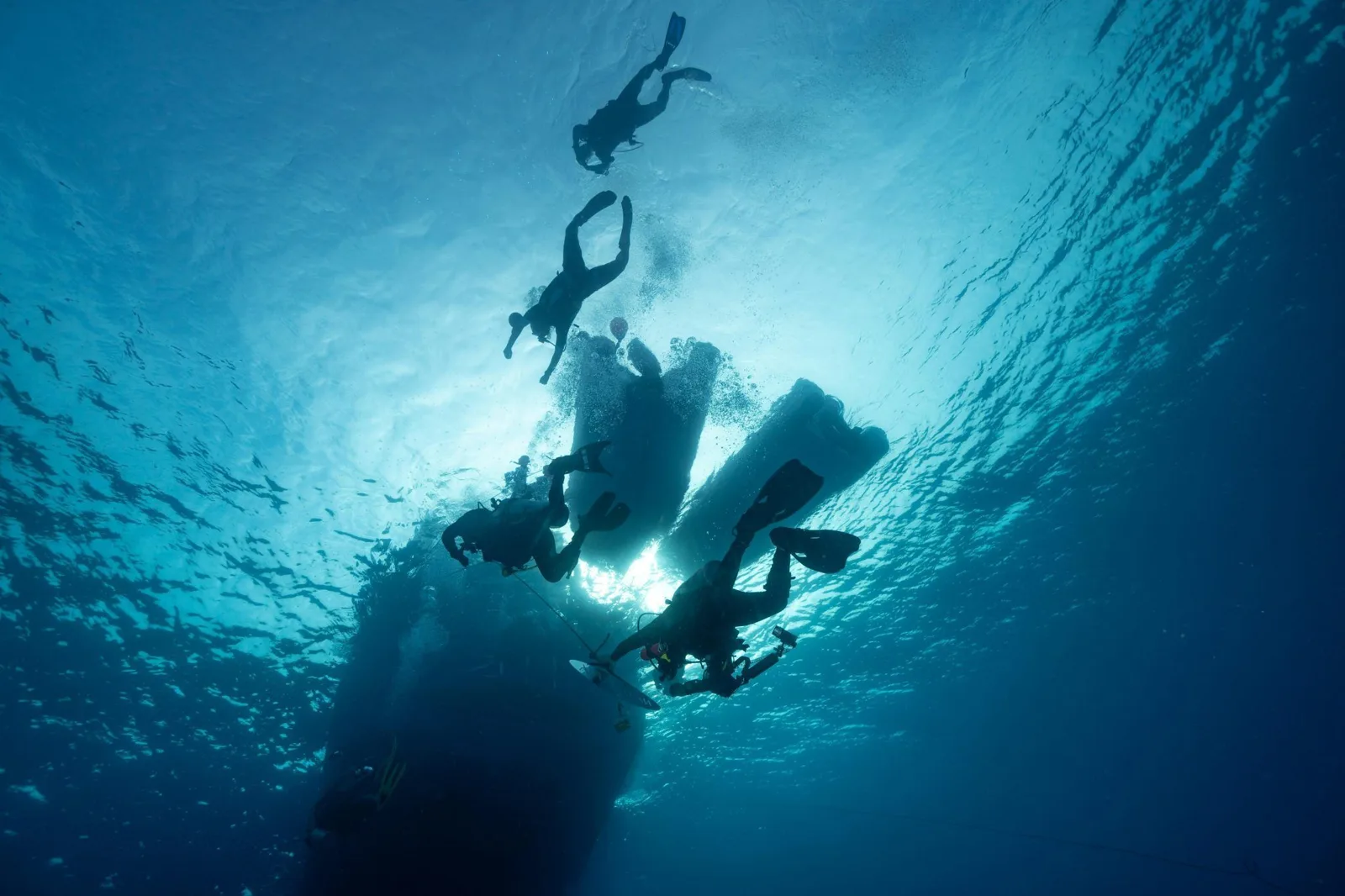 Plongeurs explorant une épave sous-marine dans une eau bleue claire
