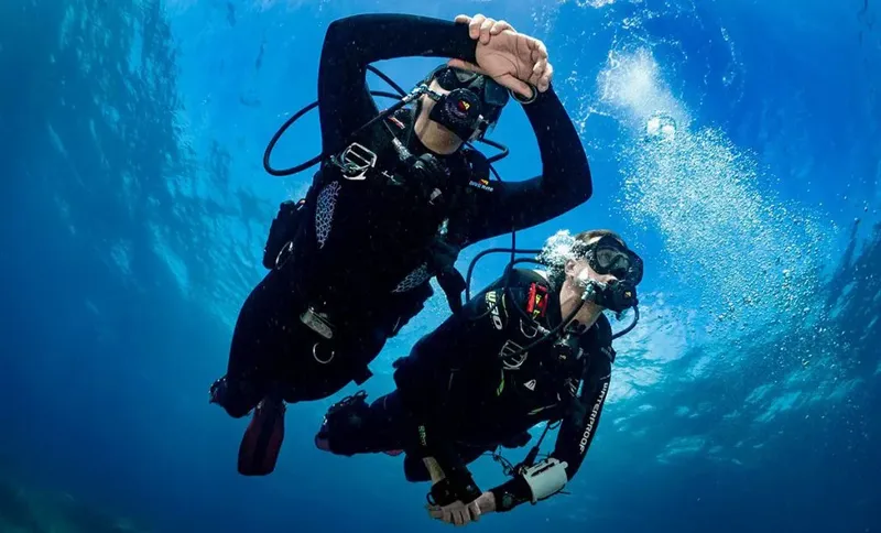 Deux plongeurs en combinaison explorent les profondeurs bleues sous-marines