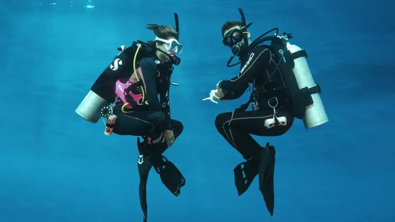 Deux plongeurs en combinaison face à face dans l'eau bleue