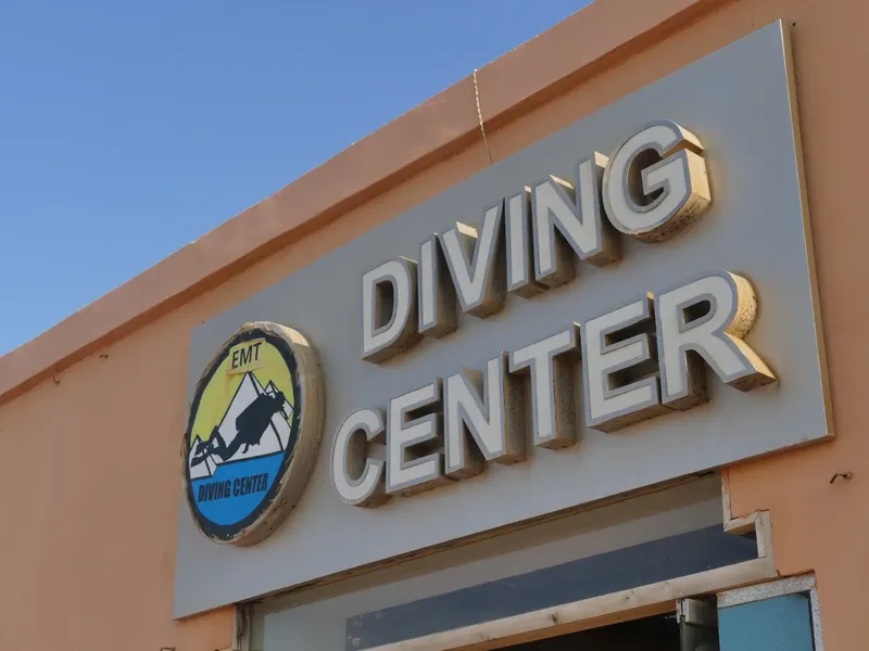 Enseigne DIVING CENTER sur mur ocre avec logo et montagne stylisée
