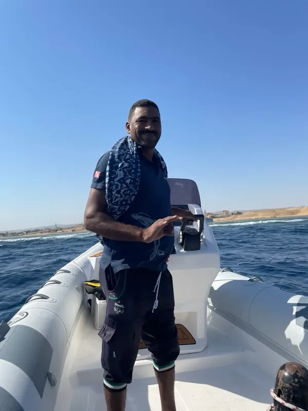 Homme souriant sur un bateau pneumatique en mer, ciel bleu