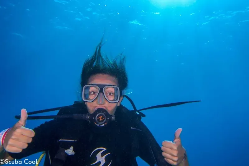 Plongeur souriant avec signe de validation, cheveux flottants, bleu profond