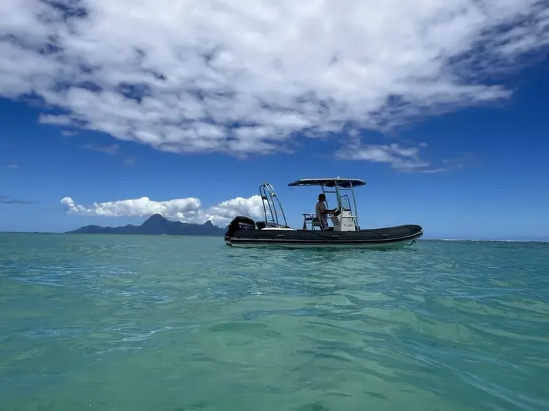 Bateau semi-rigide navigue sur une eau turquoise sous un ciel nuageux