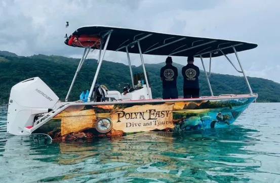 Bateau de plongée avec deux personnes à bord, paysage montagneux en arrière-plan