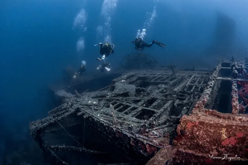 Trois plongeurs explorent l'épave d'un navire en mer profonde