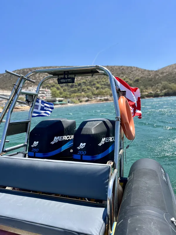 Bateau semi-rigide bleu et noir amarré en mer, drapeaux grecs et de plongee