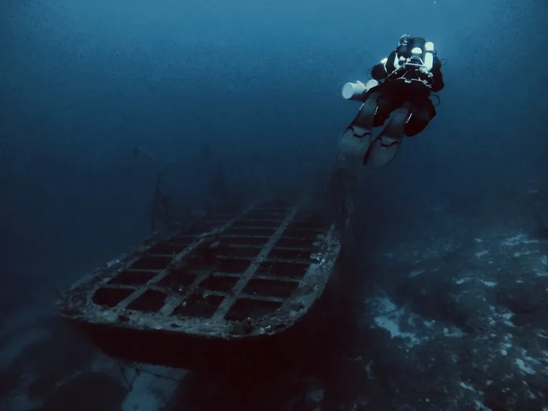 Plongeur explorant l'épave d'un navire sous l'eau bleu profond