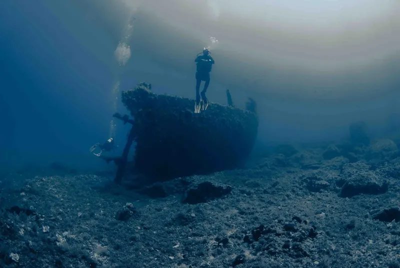 Deux plongeurs explorent une épave sombre au fond de l'océan